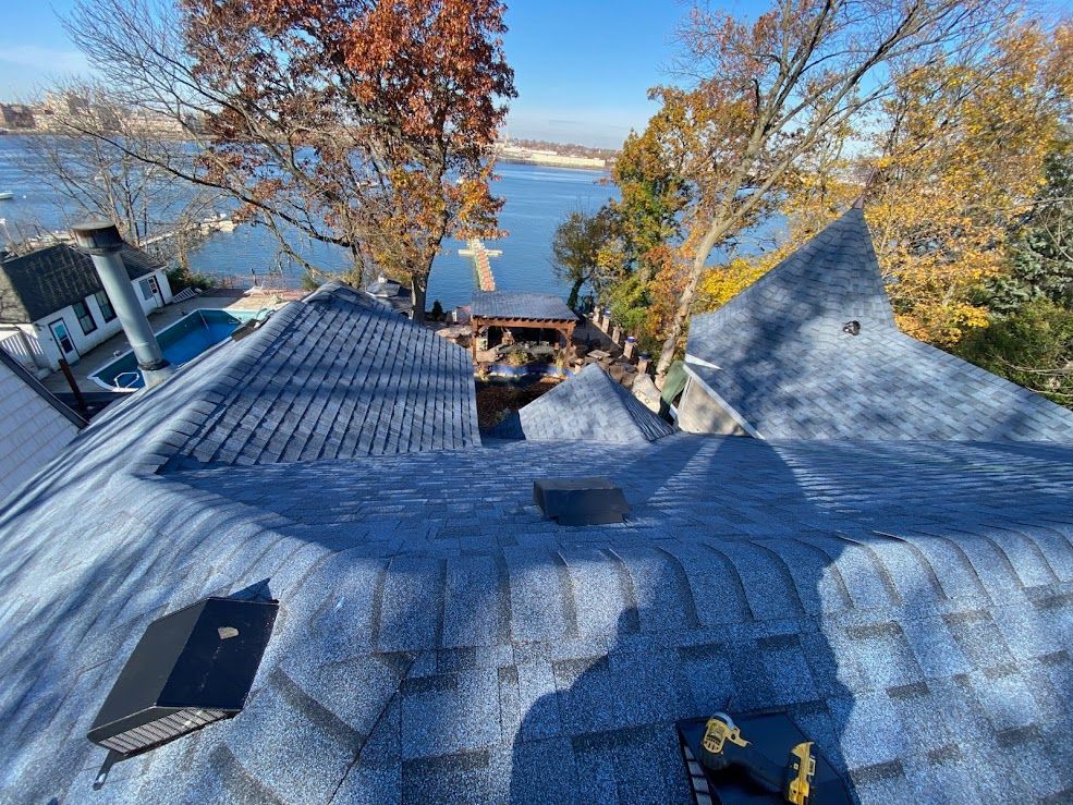 Woman in straw hat smiles, holding wine glass near a lake.