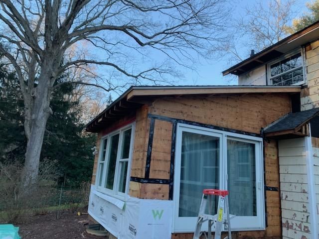 House exterior with window installation in progress; ladder present.