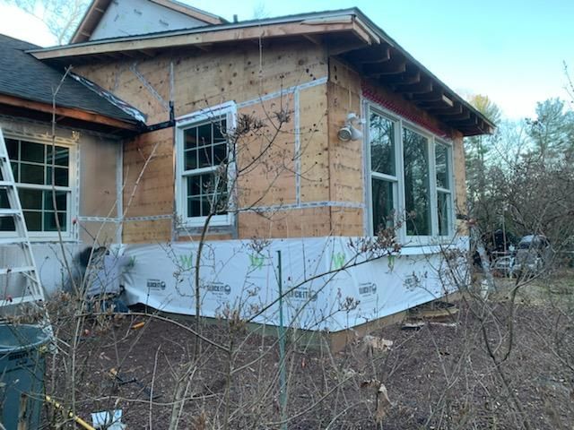 Construction site: exterior wall with windows, covered in plywood and weather wrap.