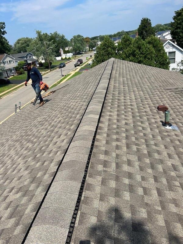 Woman in straw hat smiles, holding wine glass near a lake.