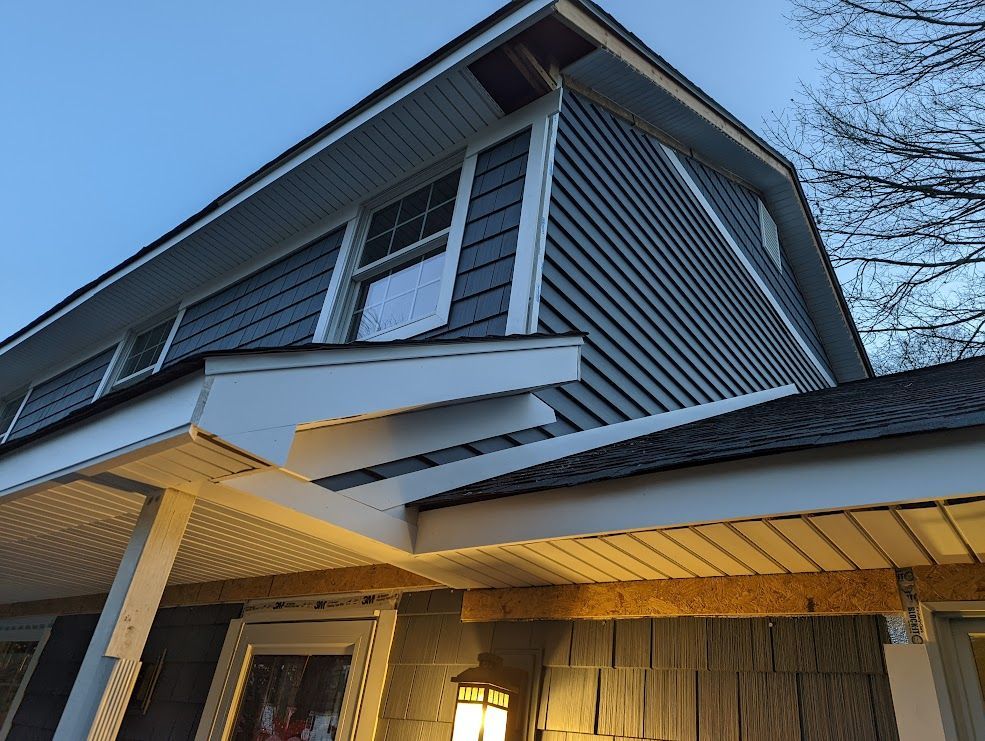 Two-story house with blue siding, white trim, and a porch under a clear sky.