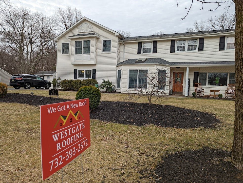 A house with a Westgate Roofing sign in front. Black truck in the background, cloudy sky.