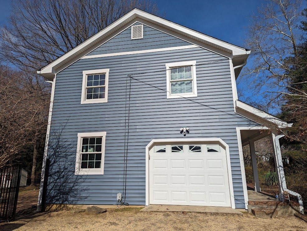 Two-story blue house with white trim, garage door, and windows.