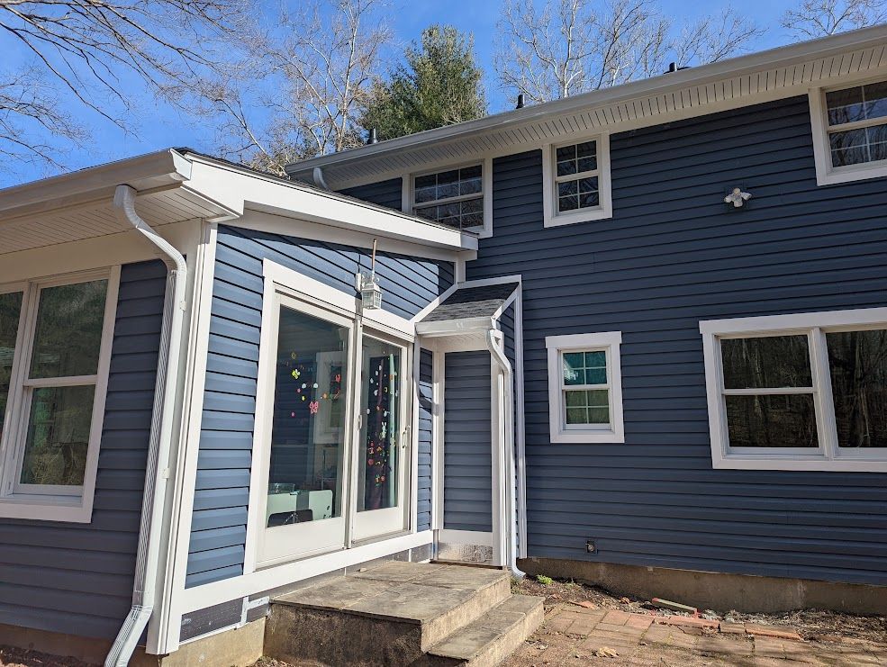 Blue house with white trim, glass doors, and windows, on a sunny day.