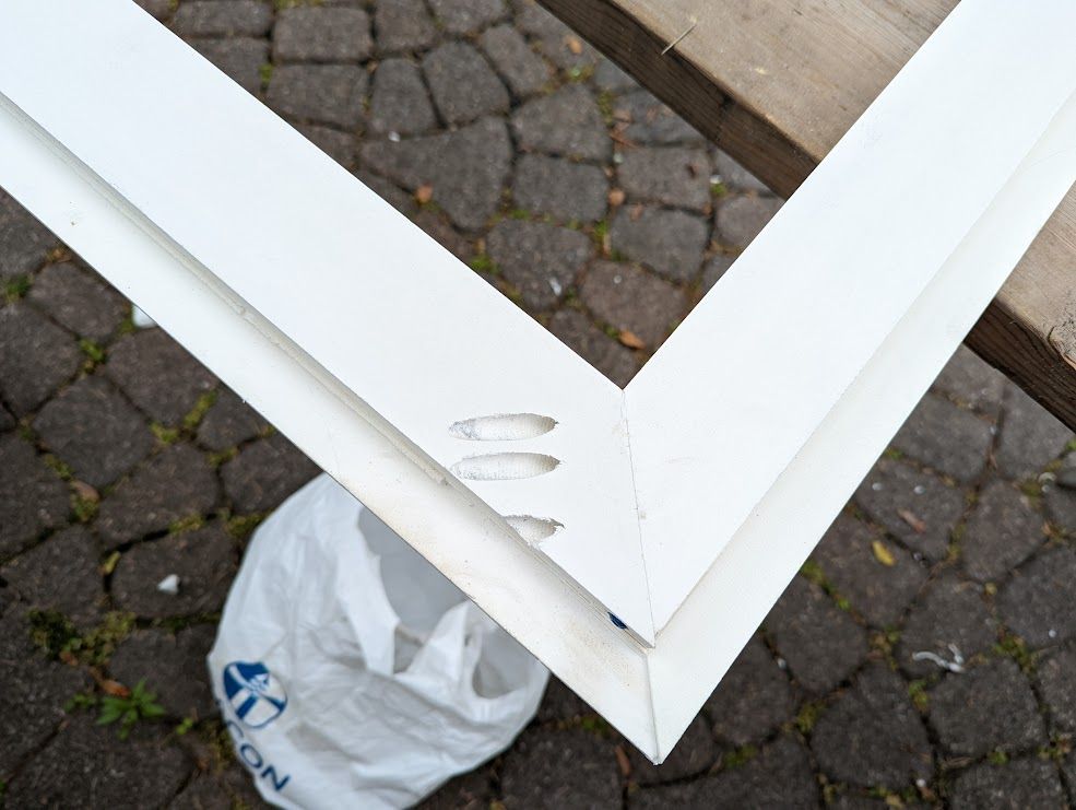 White painted wooden frame with pocket holes, on a stone patio, with a white bag.