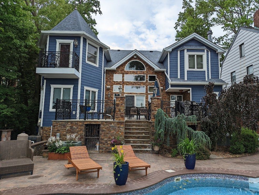 Blue and stone house with pool and deck; two lounge chairs are in front.