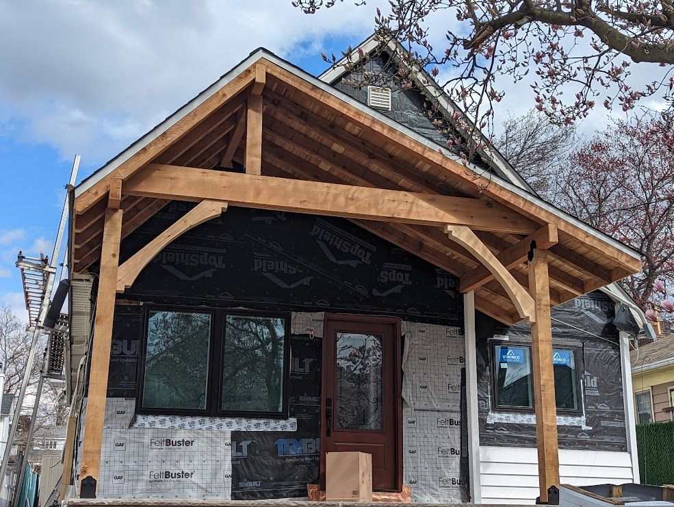 House under construction with new wooden porch. Black weather barrier visible.