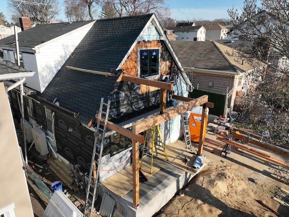 House under construction with exposed framing, deck, and partially installed roofing.
