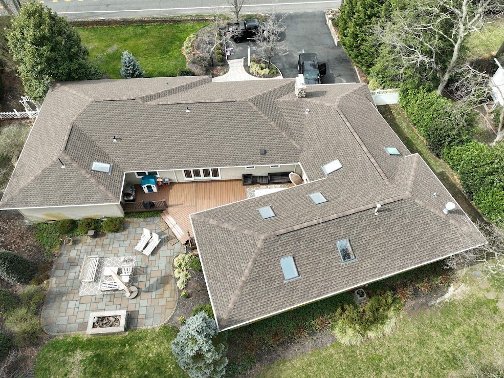 Aerial view of a brown-roofed house with a deck and patio.