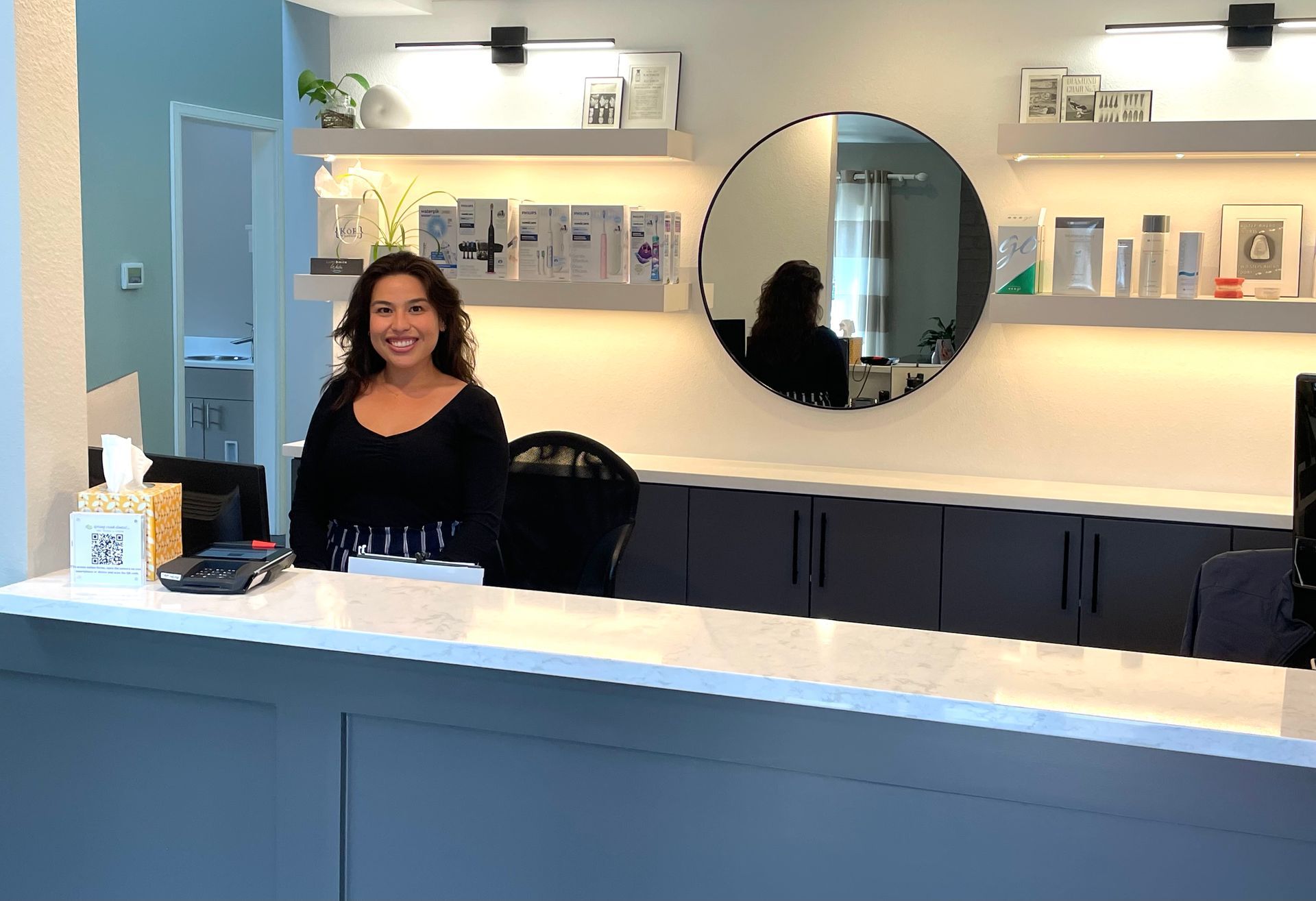 A woman is standing behind a counter in a dental office.