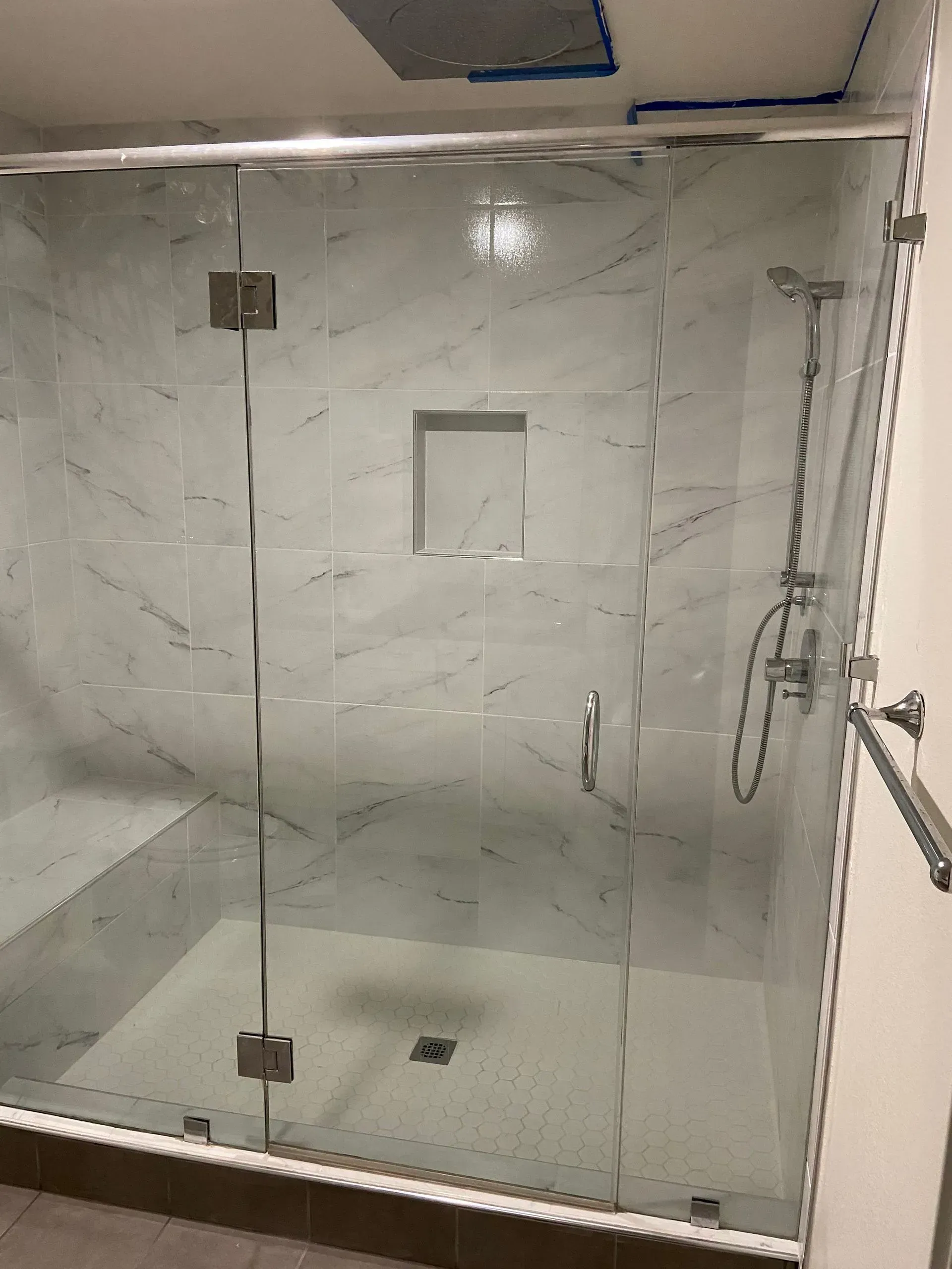 A bathroom with a walk in shower with a glass door.