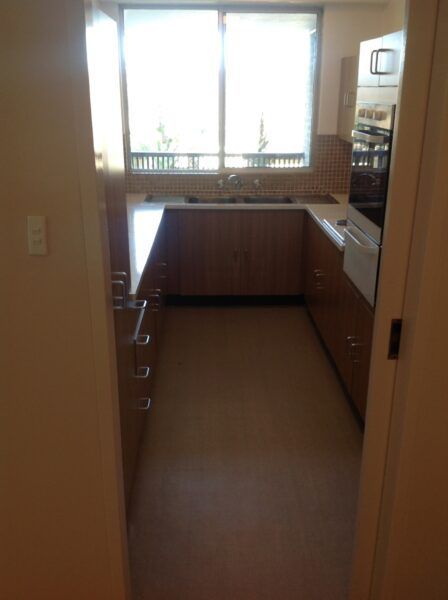 A Kitchen With Wooden Cabinets and a Large Window — Dowdy Constructions in Forster, NSW