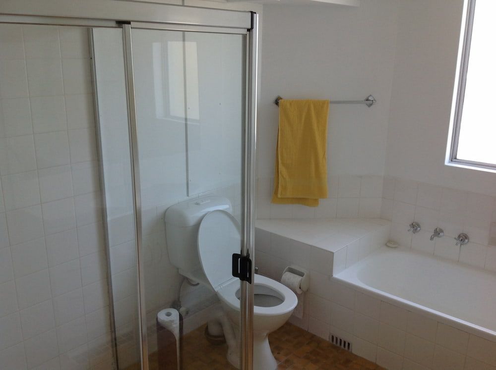 A Bathroom With a Toilet a Bathtub and a Yellow Towel — Dowdy Constructions in Forster, NSW