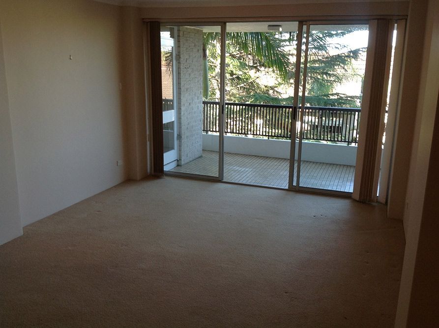 An Empty Room With Sliding Glass Doors Leading to a Balcony — Dowdy Constructions in Forster, NSW