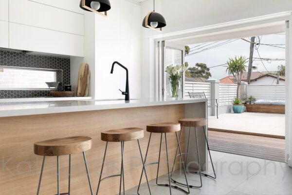 A Kitchen With Wooden Stools and White Cabinets — Dowdy Constructions in Forster, NSW