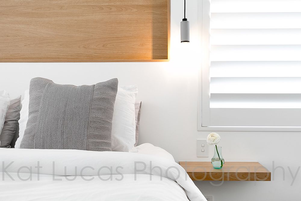 A Bedroom With a Bed, Nightstand, Window and Shutters — Dowdy Constructions in Forster, NSW