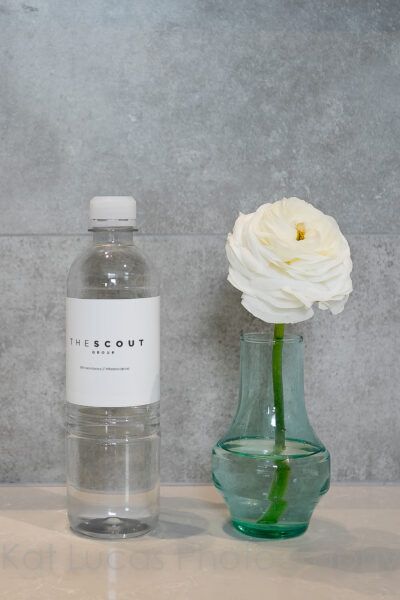 A Bottle of Water Next to a Vase With a White Flower in It — Dowdy Constructions in Forster, NSW