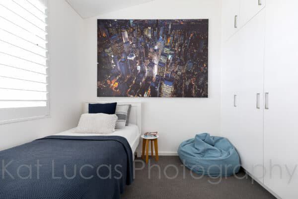 A Bedroom With a Single Bed and a Large Painting on the Wall — Dowdy Constructions in Forster, NSW