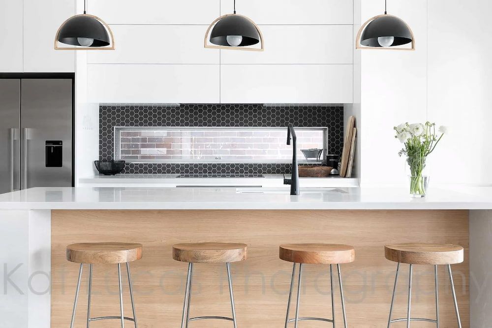 A Kitchen With White Cabinets and Wooden Stools — Dowdy Constructions in Forster, NSW