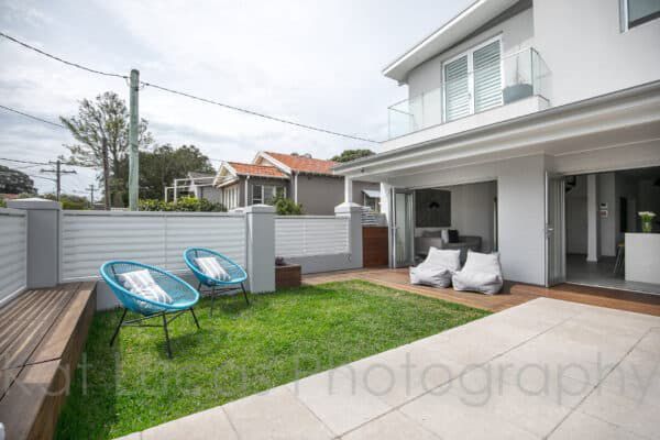 A White House With a Lawn and Chairs in Front of It — Dowdy Constructions in Forster, NSW