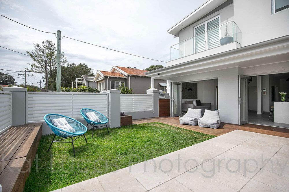 A White House With a Lawn and Chairs in Front of It — Dowdy Constructions in Forster, NSW
