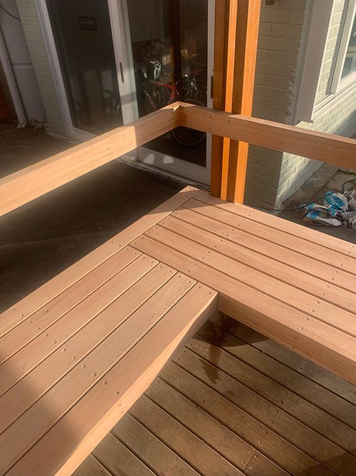 A Wooden Deck With a Bench and a Sliding Glass Door — Dowdy Constructions in Forster, NSW