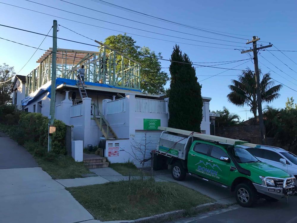 A Green Truck is Parked in Front of a House Under Construction — Dowdy Constructions in Forster, NSW