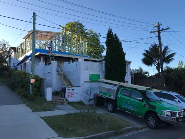 A Green Truck is Parked in Front of a House Under Construction — Dowdy Constructions in Forster, NSW