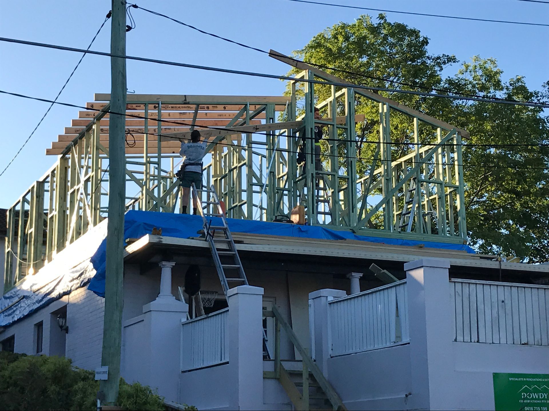 Two People Are Walking in Front of a House With a Car Parked in Front of It — Dowdy Constructions in Forster, NSW