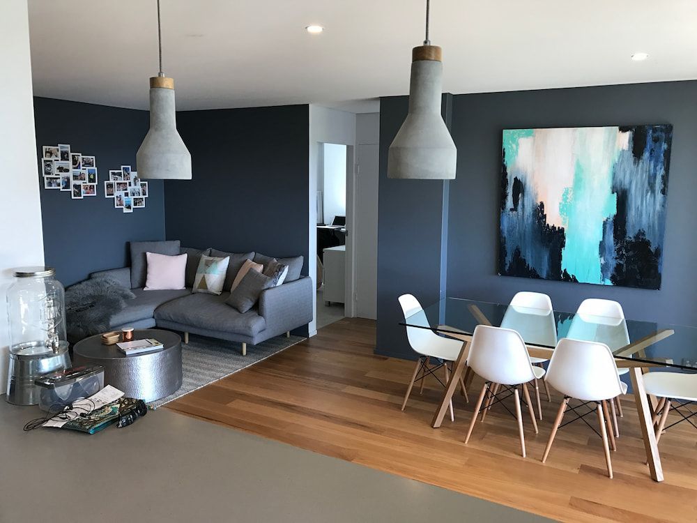 A Living Room With a Couch, Table and Chairs and a Painting on the Wall — Dowdy Constructions in Forster, NSW