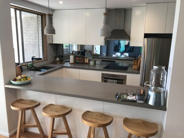 A Kitchen With White Cabinets and Wooden Stools — Dowdy Constructions in Forster, NSW