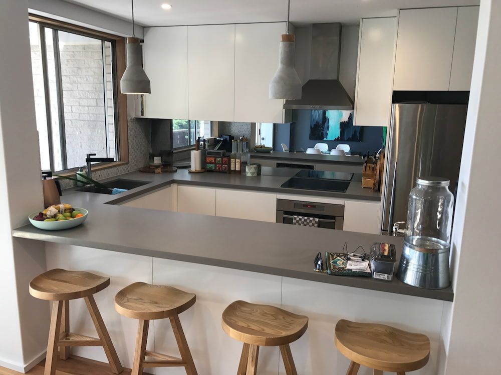 A Kitchen With White Cabinets and Wooden Stools — Dowdy Constructions in Forster, NSW