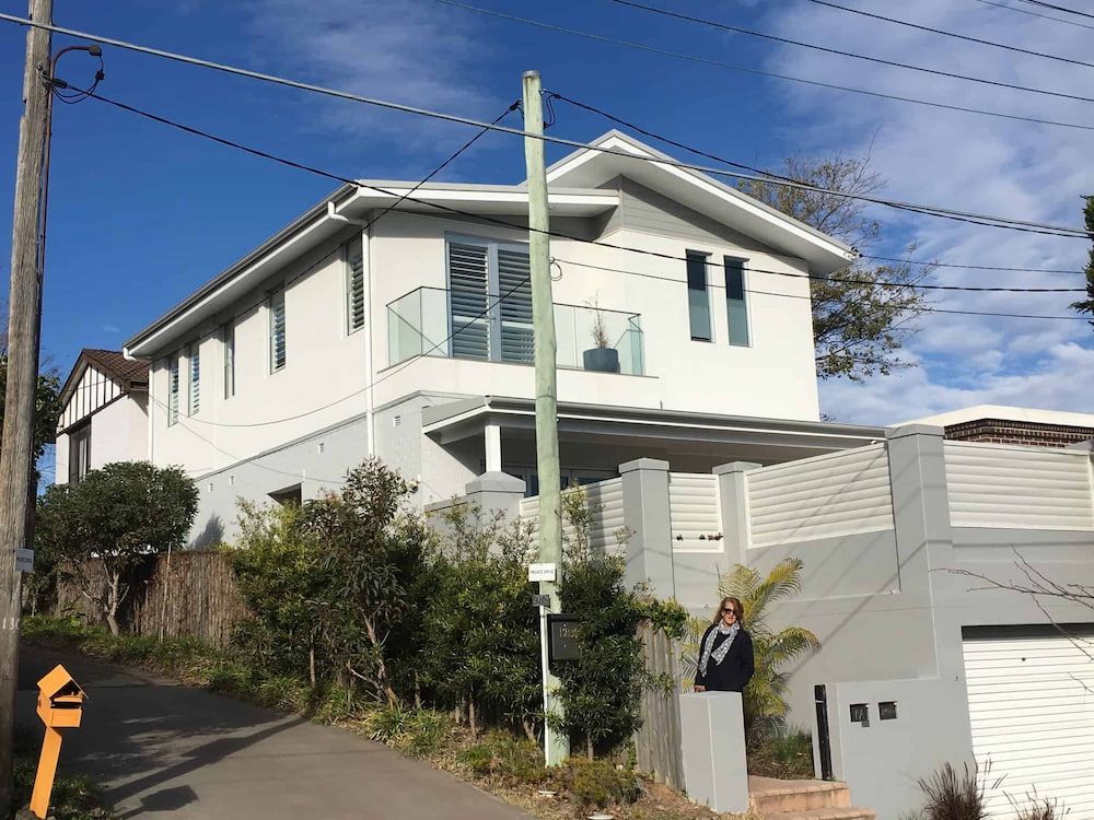 A Large White House is Sitting on Top of a Hill — Dowdy Constructions in Forster, NSW