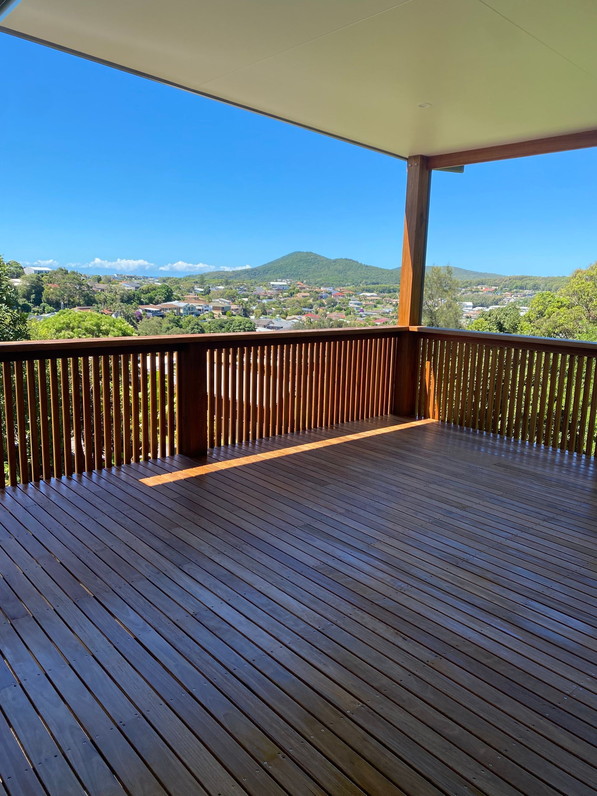 A Wooden Deck With Stairs and a Bench in the Backyard of a House — Dowdy Constructions in Forster, NSW