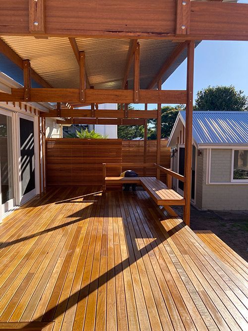 A Wooden Deck With a Bench and a Fence in Front of a House — Dowdy Constructions in Forster, NSW