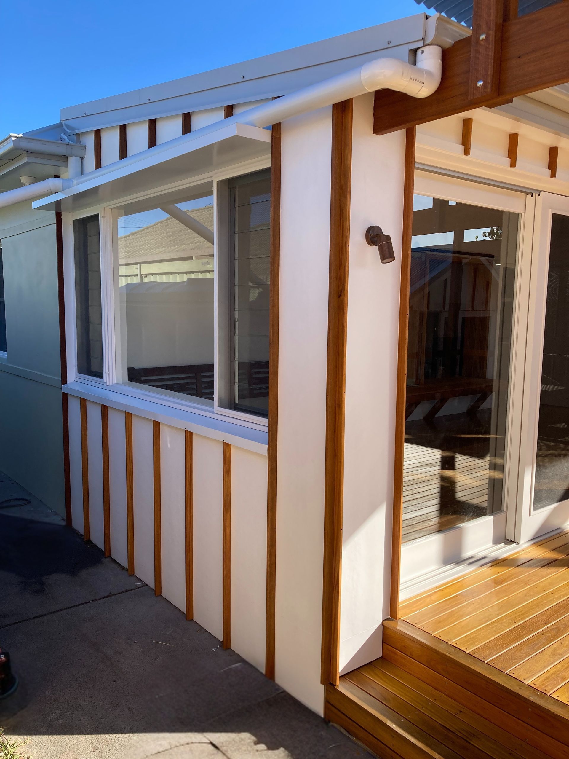 A Wooden Window With a Brick Wall Behind It — Dowdy Constructions in Forster, NSW