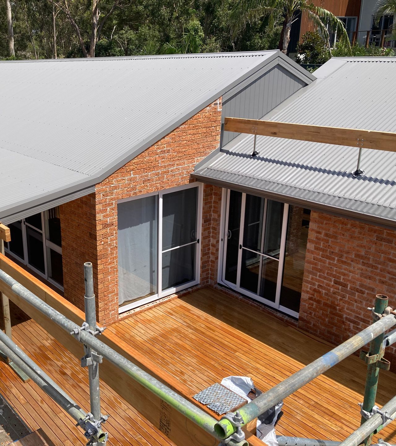 A wooden deck with a pergola and a fence in front of a house — Dowdy Constructions in Forster, NSW