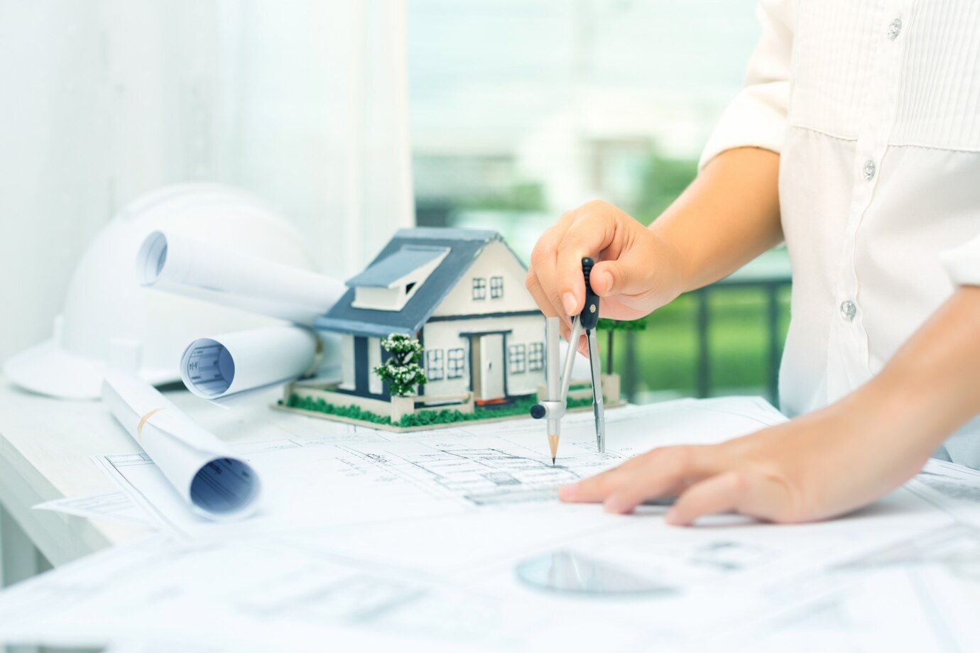 A Person is Drawing a House on a Blueprint With a Compass — Dowdy Constructions in Forster, NSW