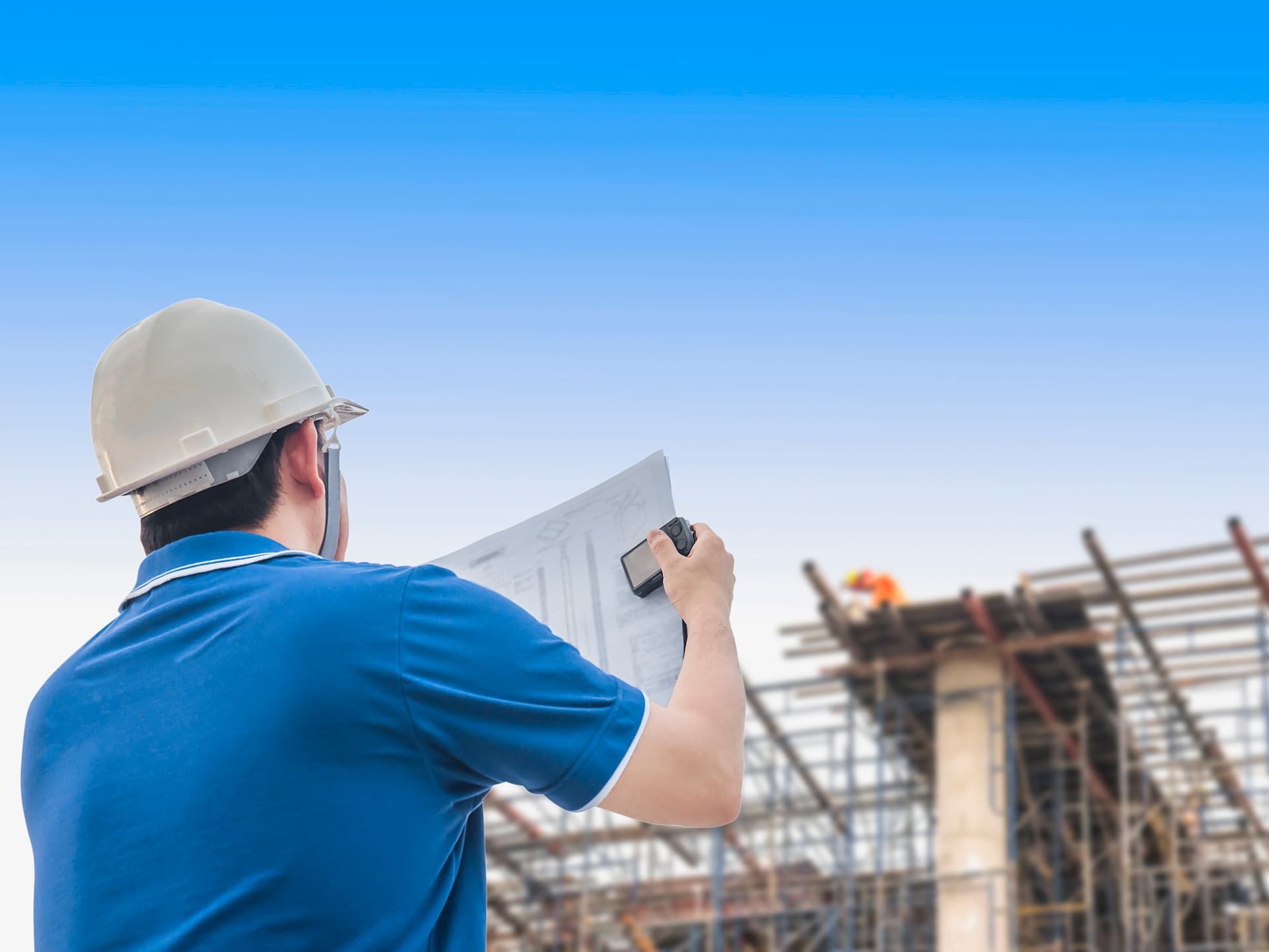 A Construction Worker is Looking at a Blueprint at a Construction Site — Dowdy Constructions in Forster, NSW