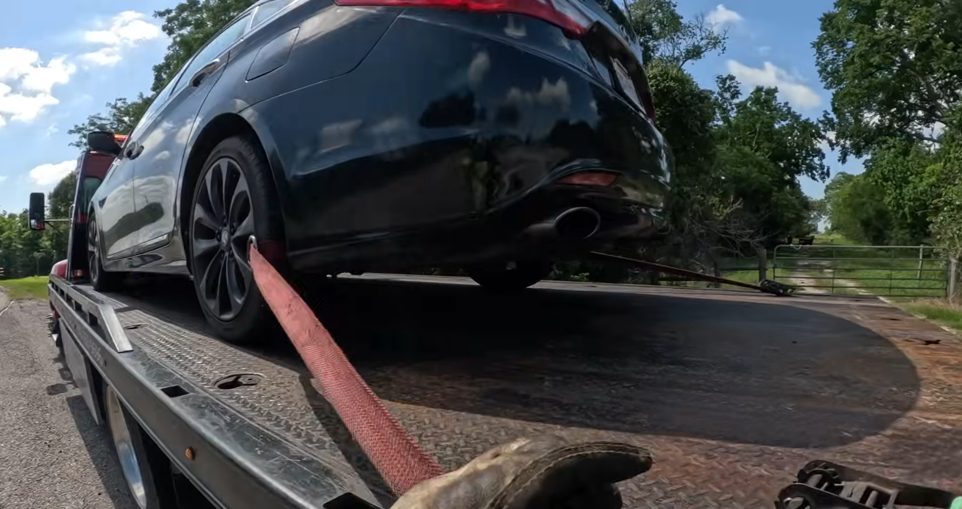 Car being loaded and strapped on flatbed for towing