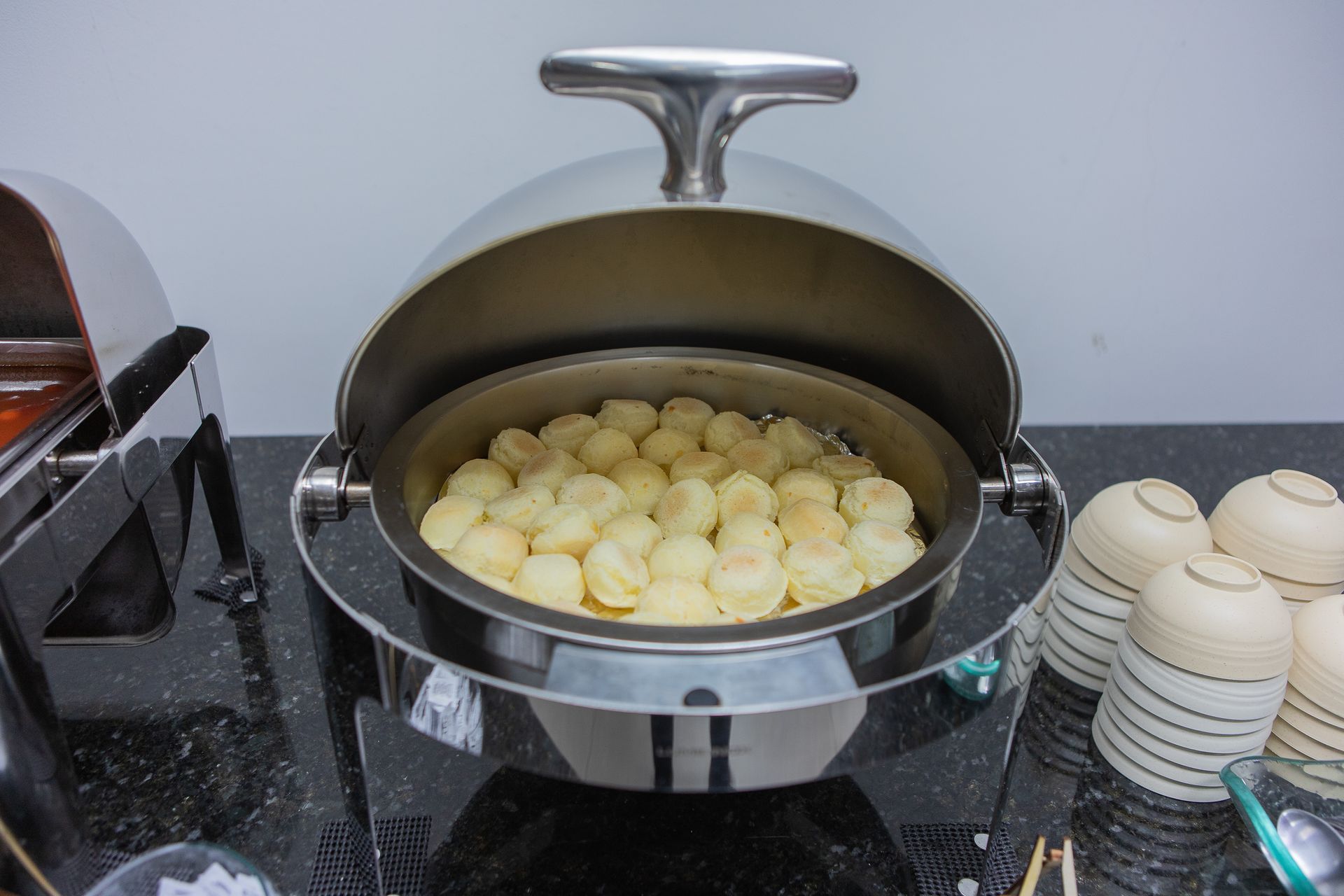 Um aquecedor de buffet em aço inoxidável que comporta uma grande porção de alimentos pequenos, redondos e de cor clara.