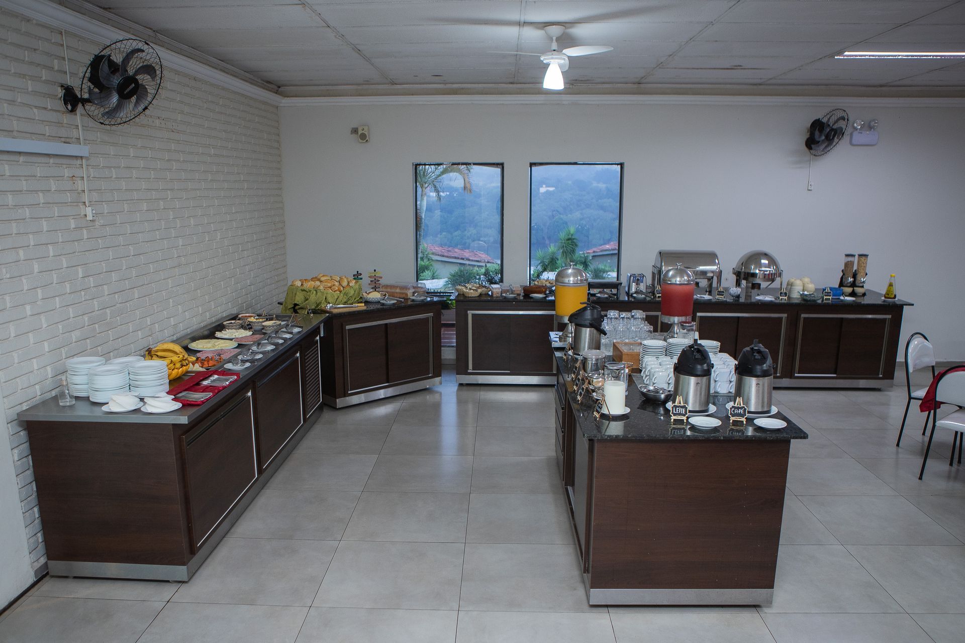 Buffet montado em uma sala de jantar com comida disposta em mesas de serviço de madeira escura.