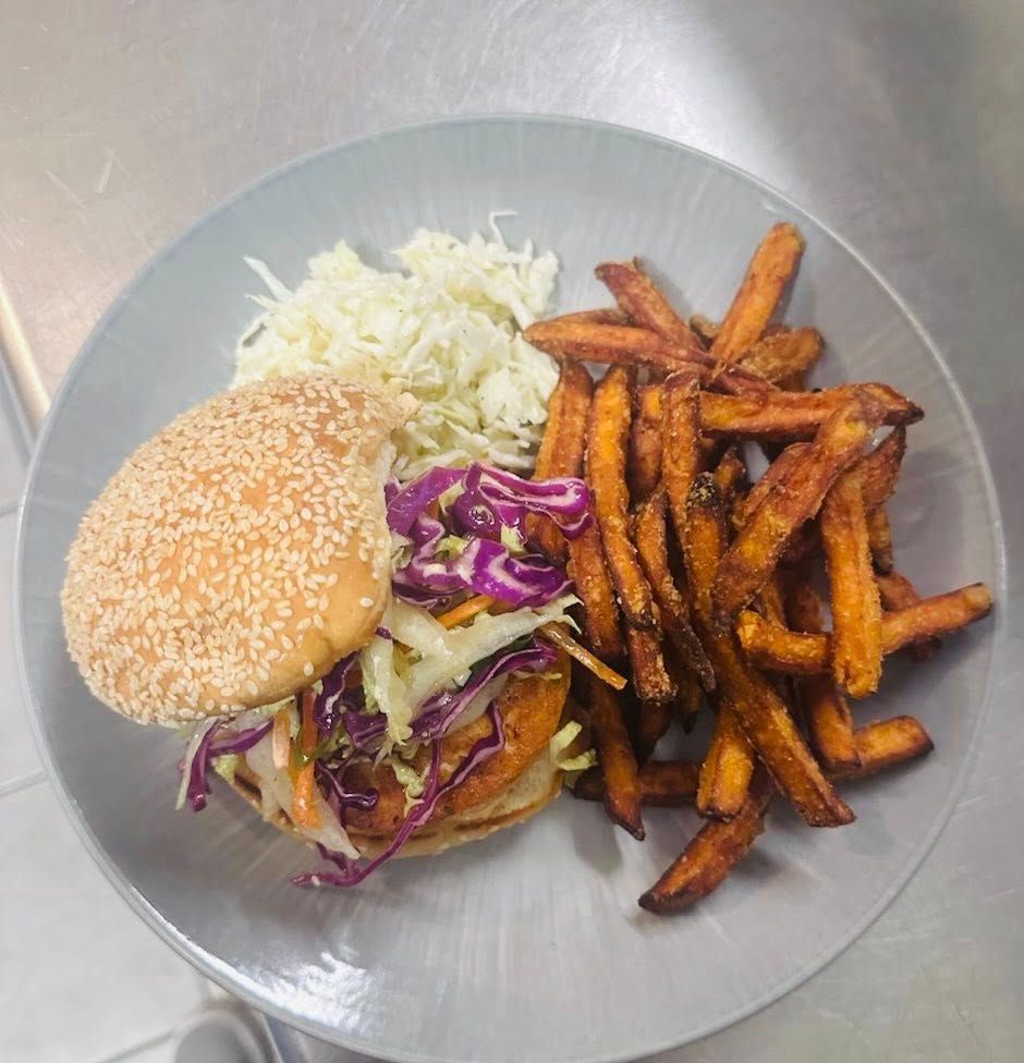 Burger with sweet potato fries and coleslaw on a plate.