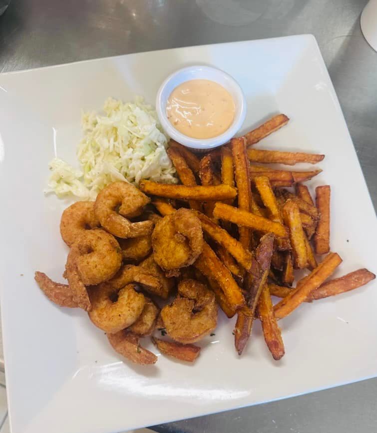 Plate with seasoned shrimp, sweet potato fries, coleslaw, and dipping sauce.