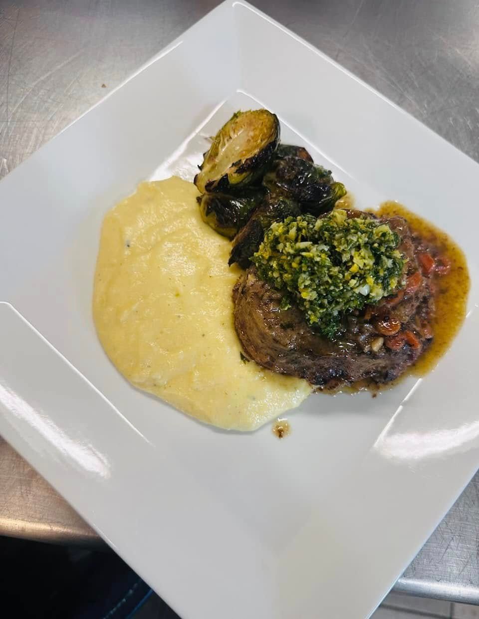 Plate with steak topped with green sauce, polenta, and roasted Brussels sprouts.