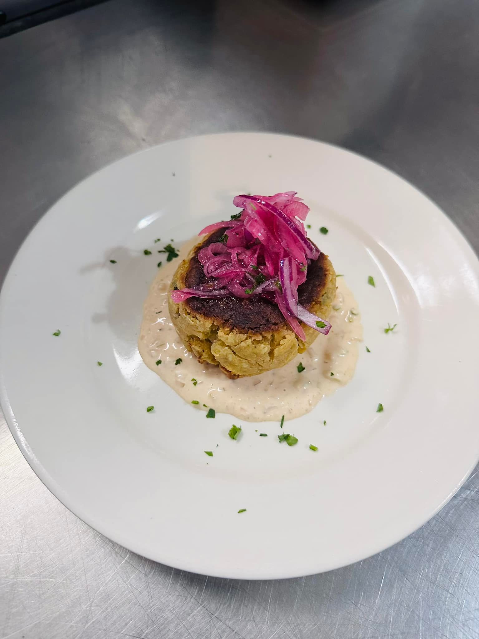 Falafel with pickled onions and sauce, served on a white plate.