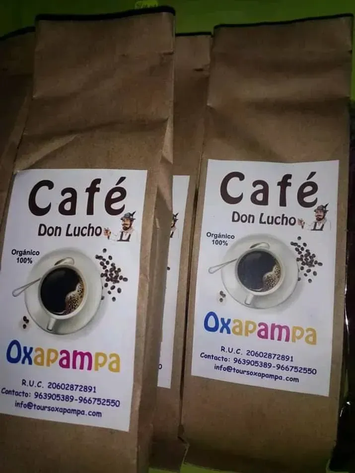 Dos bolsas de café marrones con las etiquetas “Café Don Lucho” y “Oxapampa” sobre una mesa.