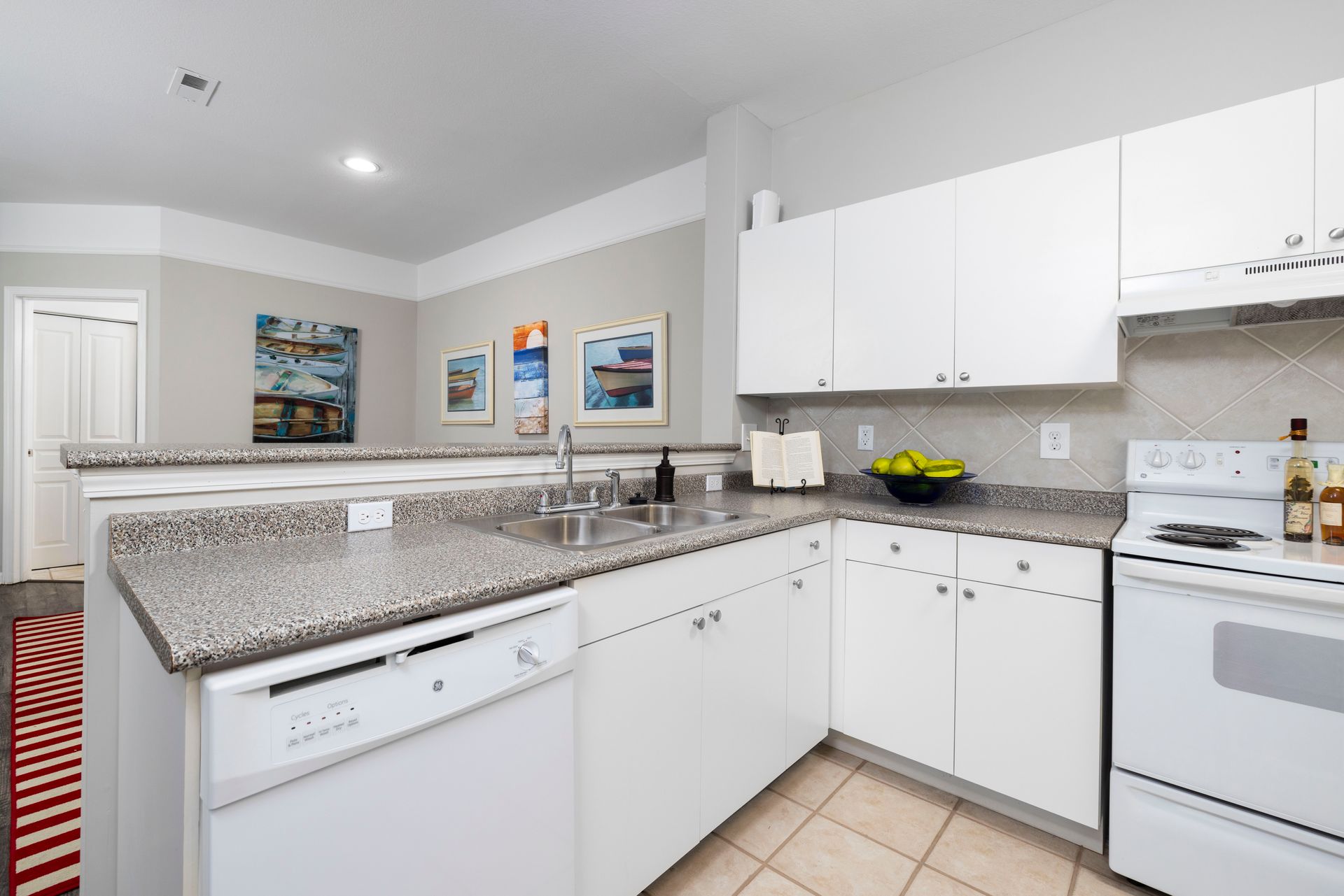 A kitchen with white cabinets , a stove , a sink , and a dishwasher | The Grove at Oakbrook