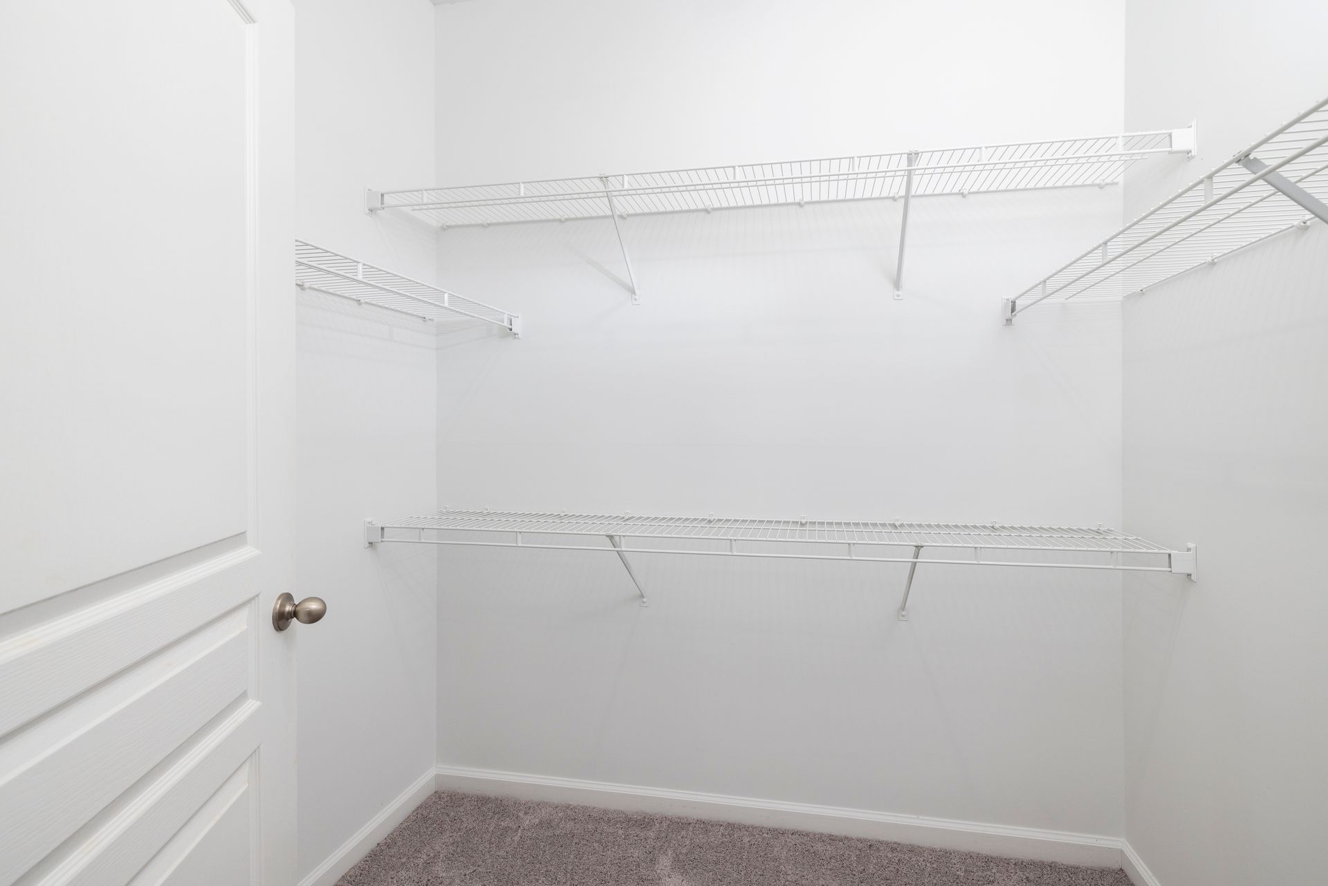 A walk in closet with lots of shelves and a door | The Grove at Oakbrook