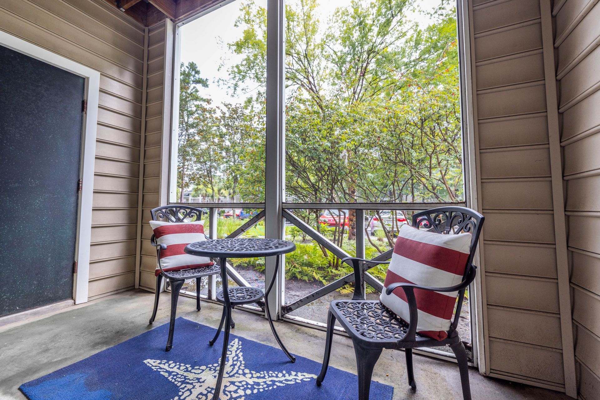 A screened in porch with two chairs and a table | The Grove at Oakbrook